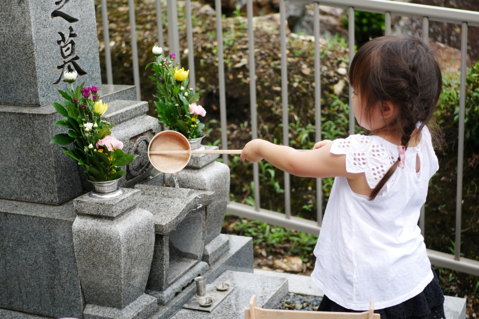 お盆にお墓参りをする子供