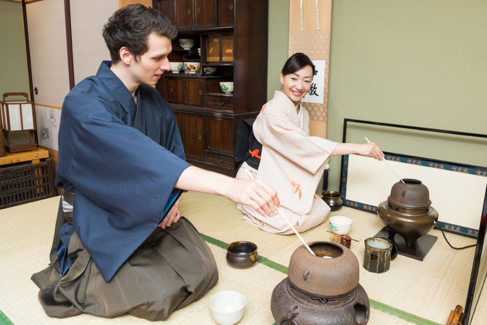 和室で茶道体験を行う外国人参加者と指導する日本人の様子